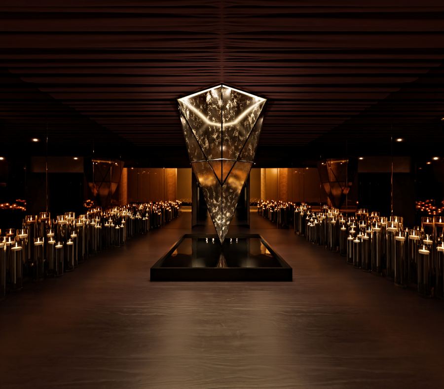 Pasillo de velas hacia una escultura de cristal iluminada